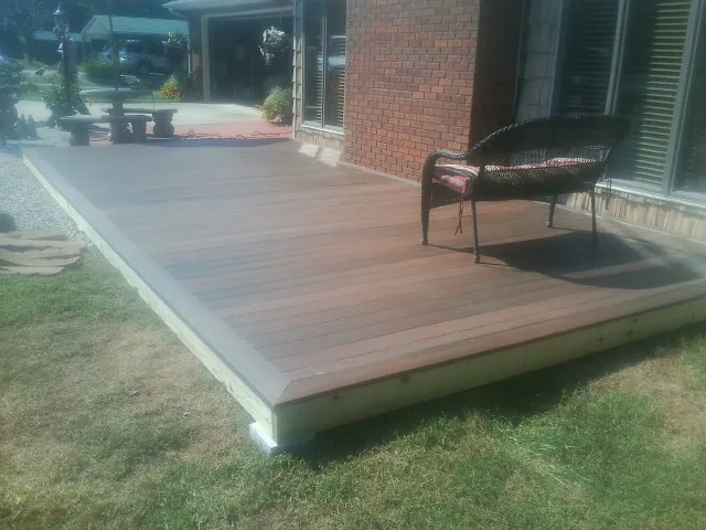 New wood deck and wicker chair beside a brick house in Galt